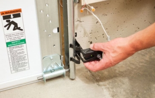 Hand inspecting garage door sensor.