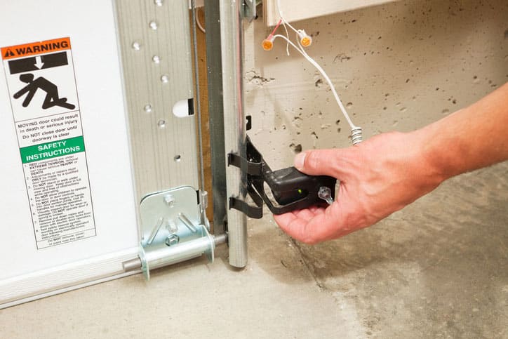 Hand inspecting garage door sensor.