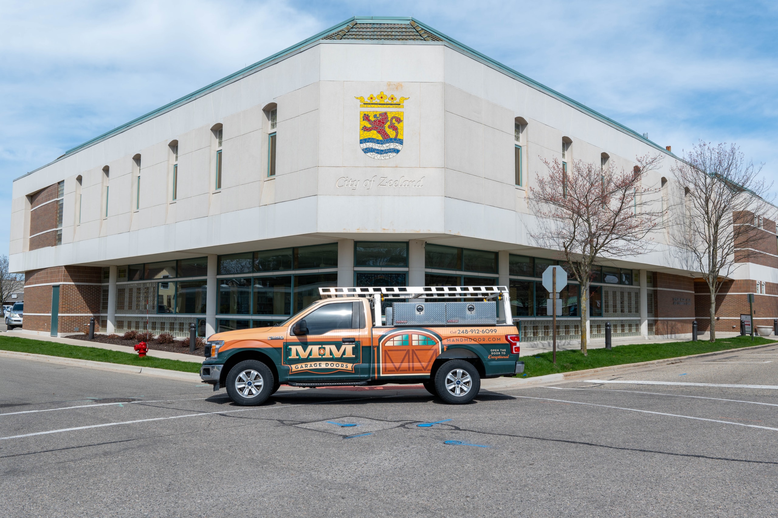 A truck with "MGM Exteriors" branding is parked outside a white municipal building labeled "City of Midland" on a clear day.