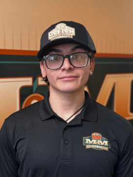 A person wearing glasses, a black cap, and a black polo shirt with the "MMM" logo stands in front of a matching branded backdrop. | M&M Garage Doors